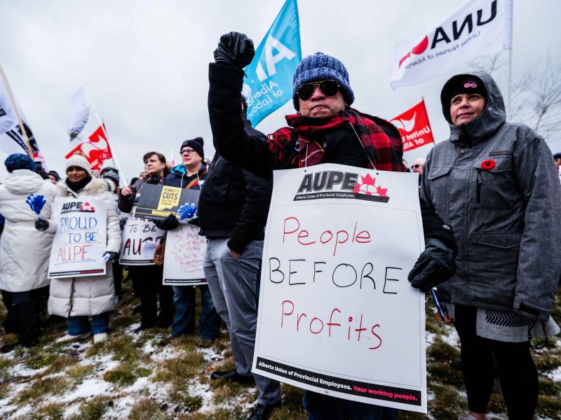 AUPE members at a rally, one member holding a sign that says &quot;people before profit&quot;