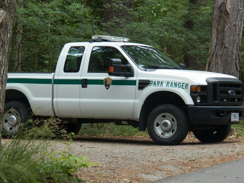 a truck with a park ranger logo sits among trees