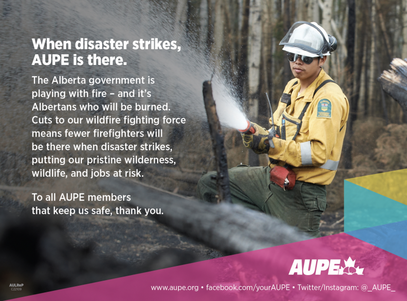 An AUPE member in firefighting gear wields a large water hose amidst a charred forest