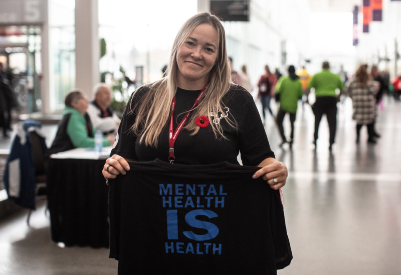 A Local 003 delegate hold up a t-shirt that says "Mental Health is Health"